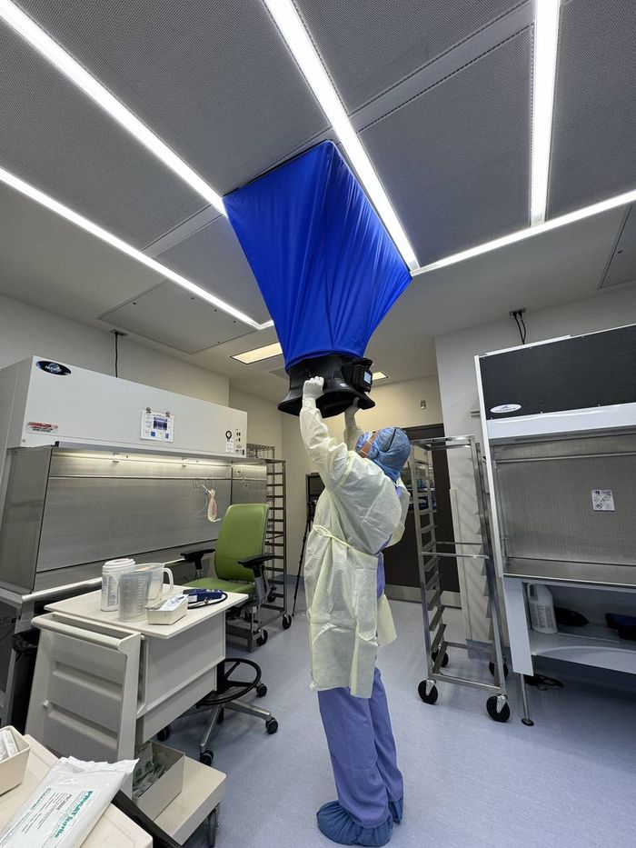 Technician performing capture hood test on supply diffuser in a pharmaceutical cleanroom