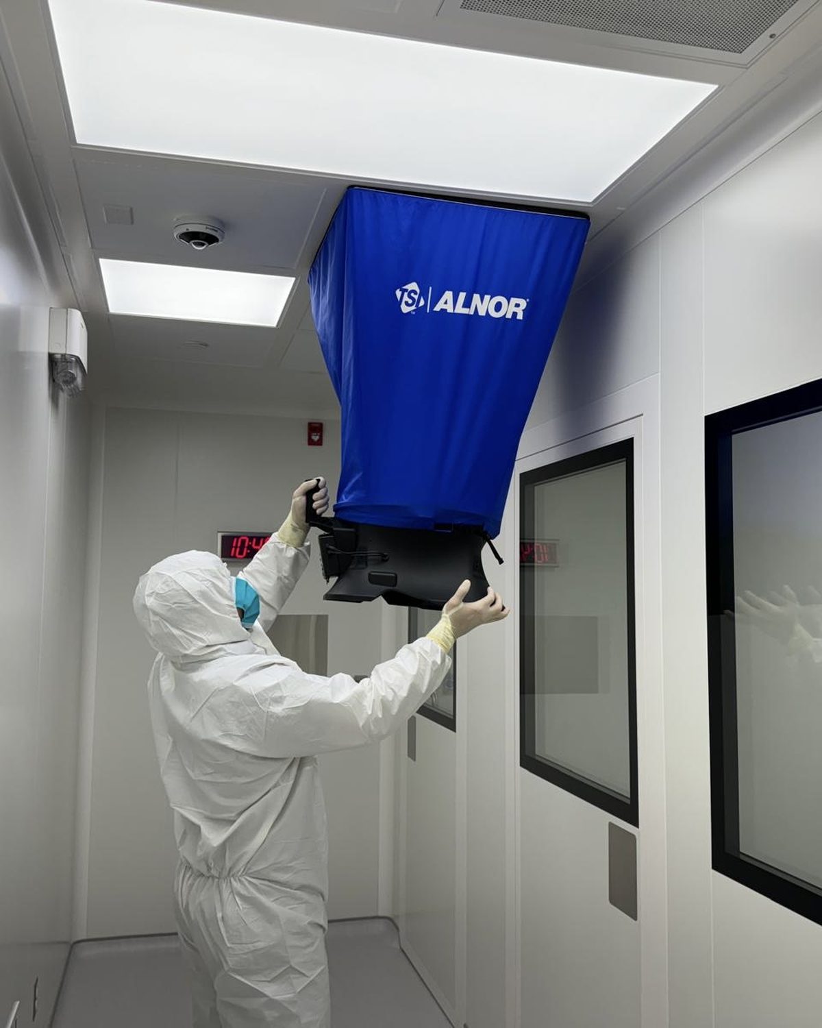CAM technician taking HEPA supply airflow volume readings with a capture hood in a sterile compounding cleanroom
