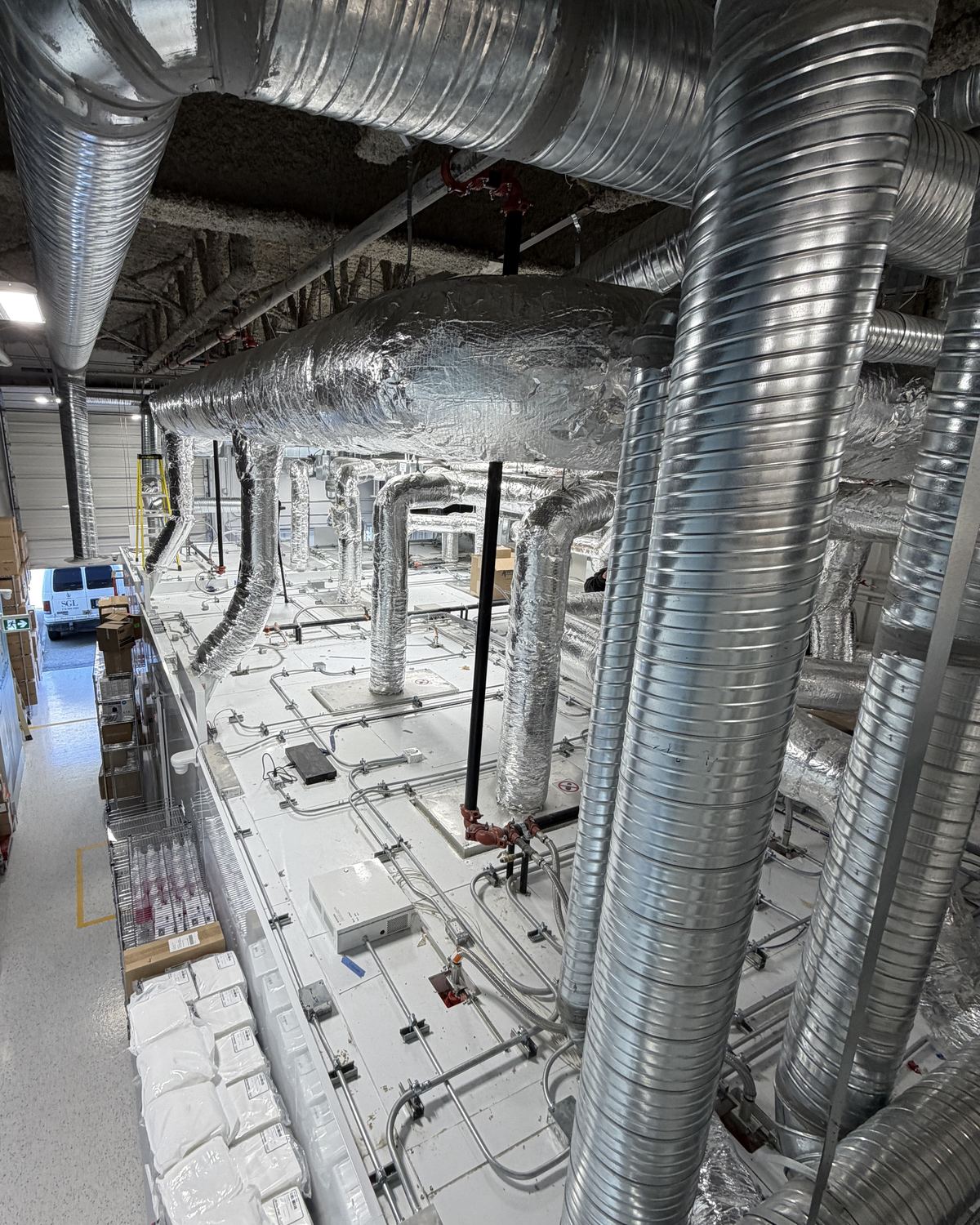 Overhead view of a modular cleanroom showing HEPA filter housings and spiral ductwork serving every room penetration